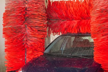 Araba yıkama makinesi. Otomatik yıkama istasyonunda otomatik fırçayla temizlenmiş mavi araba. Otomatik oto yıkama makinesi arkaplanı.