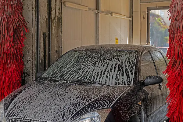 Car washing machine. Auto brush washer clean blue car on automatic carwash station. Automated car washing machine background.