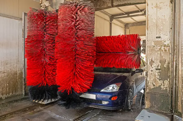Car washing machine. Auto brush washer clean blue car on automatic carwash station. Automated car washing machine background.