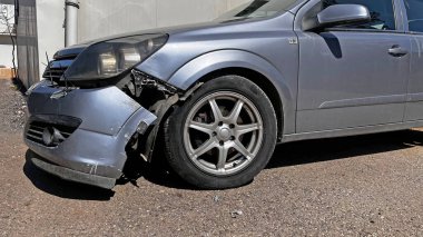 Ön tarafı parçalanmış, plakası kırılmış gümüş renkli bir araba. Hasarlı kısmın ayrıntıları..