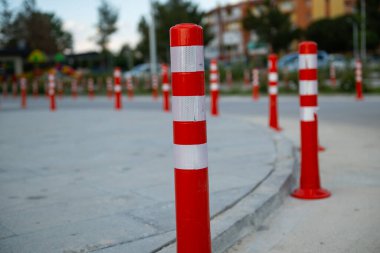 Turuncu trafik konisi, park etmek yasak. Plastik kırmızı bariyer. Kırmızı ve beyaz sıra trafik bariyeri yolda. Asfalt yolda yansıtıcı pigmentle plastik sütunlardan yapılmış bir bariyer. Tehlike kavramı.