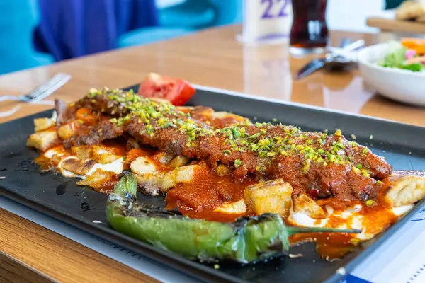 stock image Turkish kebab with pistachios served with sliced pita bread, yoghurt and tomato sauce.