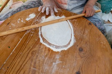 Bir kadın geleneksel Türk gözlemesi için hamur hazırlıyor.