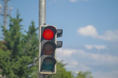 Trafik ışıklarında kırmızı renk. Arka planda bulutlu ve mavi gökyüzü..