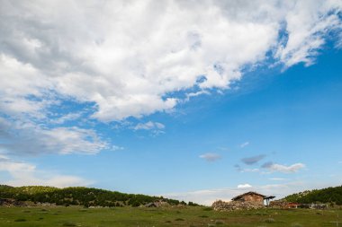 Bulutlu gökyüzü ve yeşil manzara, harika bahar manzaraları, yeşil alan ve tepe tepedeki dağ evleri manzarası.