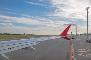 Havaalanından ayrılan bir yolcu uçağının kanadı. Arka planda bulutlu bir gökyüzü.