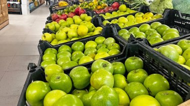 Market rafında satılık kasalarda sergilenen lezzetli yeşil elmalar..