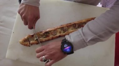 Fırında pipetler bıçakla dilimlenip servis ediliyor. Türk usulü pizza.