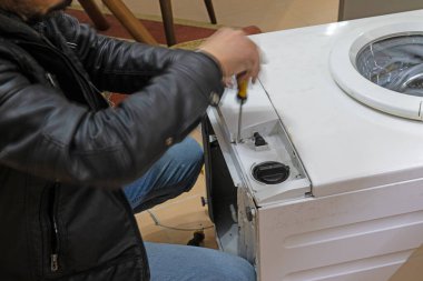 A repairman fixes a broken washing machine at home. clipart