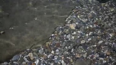 Su manzarası. Dalgalı su yüzeyi ve denizde çakıl taşları.