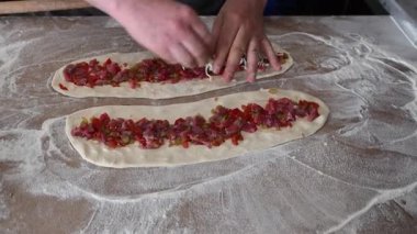 Aşçı, et ve rendelenmiş peynirli Türk usulü pide hazırlıyor..