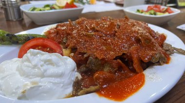 Tabakta servis edilen İskender kebabının üstünde geleneksel Türk yoğurdu..