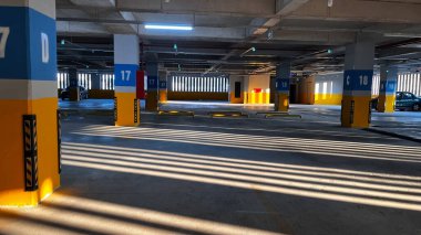 Çok katlı bir otoparkta işaretli park yerleri ve güneş ışınları..