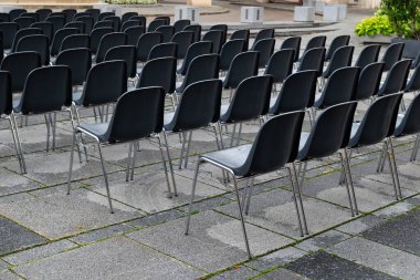 Boş plastik sandalyelerle düzenlenmiş açık hava oturma alanı, yaklaşan olaydan önceki sakinliği yansıtıyor.
