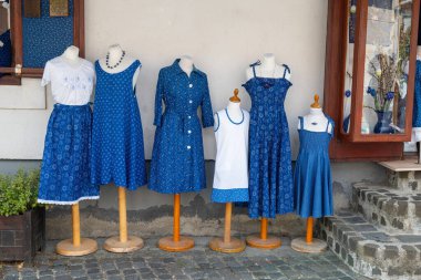 Budapeşte 'de bir mağazanın önünde sergilenen mavi ve beyaz geleneksel desenli elbise ve etekler. Halk kültürü ve el sanatları.