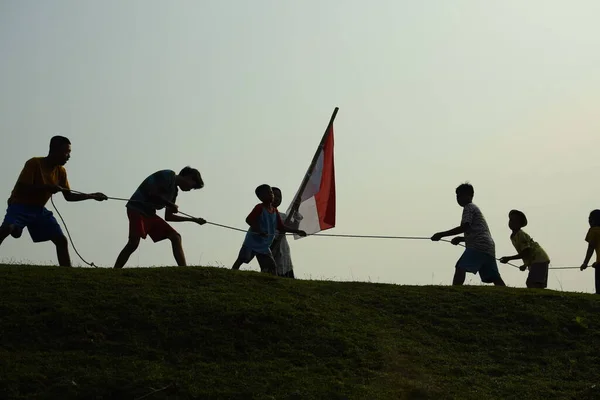 Çocuklar kırmızı ve beyaz bayrak taşırken koştu, Endonezya ulusal bayrağı. Mangerang, 6 Ağustos 2023.