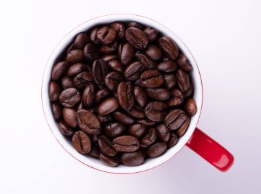 Beyaz arka planda kırmızı bardakta kahve çekirdekleri.