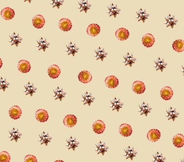 Parlak gümüş yapıştırıcı yay ve güzel sarı ve turuncu taç yaprağı çiçeği tarafından yapılan soyut tekrarlanan desen kompozisyonu. Açık sarı ya da bej arkaplan üzerindeki estetik kavram.