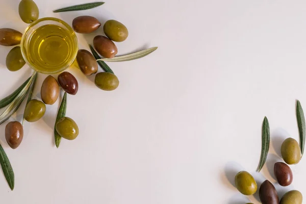Zeytin, zeytin yaprağı ve bardakta ekstra zeytinyağı temsil eden yaratıcı, minimal, doğal Akdeniz duvar kağıdı konsepti. Not alanı ile beyaz arkaplan üzerinde düz sebze bileşimi yatıyordu.