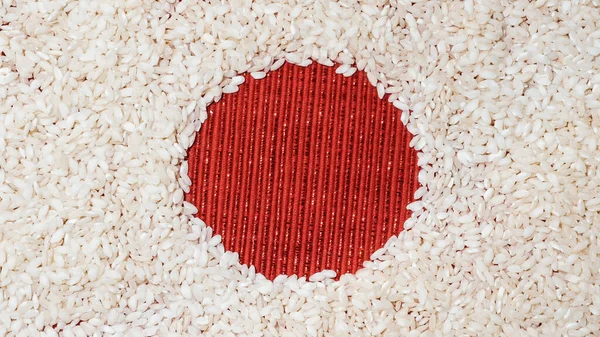 Beyaz arka plan olarak pirinç ve kırmızı tekstil dairesiyle yapılmış basit bir sanat konsepti. Tema olarak Japonya Bayrağı.