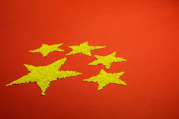 Sarı yıldızlı Çin bayrağı kırmızı arka planda sarı pirinç renginde.