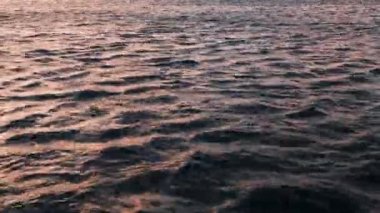 4K 'da güneşin doğuşu sahnesi. Deniz yüzeyi ve su dokusunun deniz manzarası. Doğa konulu çevre sorunları. Gökyüzü kızılımsı yansıması, dalgalar ve dalgalar huzurlu bir şekilde sıçrıyor..
