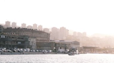 Rijeka 'nın 4k sanayi limanında romantik bir yavaş çekim videosu sabah gündoğumu altın saati bir balıkçı teknesi, gökyüzünde martılar ve arka planda gökdelenler. Bulutlu gökyüzü parlak bir deniz yansıması yapar.