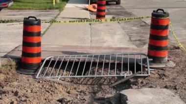 iki turuncu ve siyah trafik delinatörü varil kaldırımın yanında metal bir barikat gümüş çit ve su hattı değişimi için aralarına dikkat bandı.