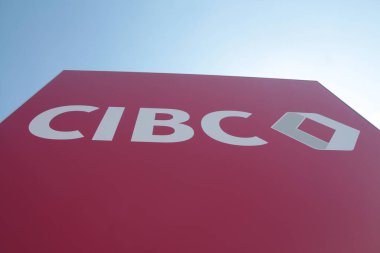 Cibc Kanada ticaret bankası tabelası, aşağıdan çekilmiş ve arka planda parlak bir gökyüzü var.