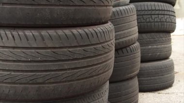 Yıpranmış ve solmuş araba lastikleri. Biri diğerinin arkasında, dışarıda kaldırımda.