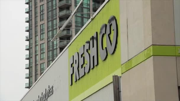 店前的新鲜食品杂货店标志 背景为公寓楼和天空 绿色和黑色 从侧面拍摄 — 图库视频影像