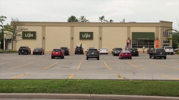 建物および正面玄関のオントリオのロゴの側面のLcboのアルコール コントロール ボード 駐車された車が付いている駐車場 広いショット — ストック動画