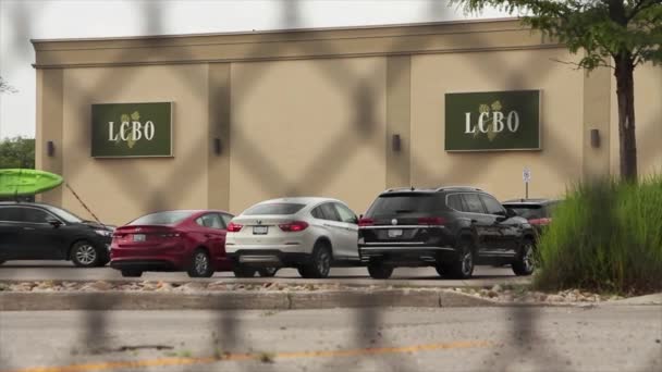 建物のオントリオのロゴの側面のLcboの液体の制御板 車が付いている駐車場およびフェンスを通って撃たれる車を引っ張ることができます — ストック動画