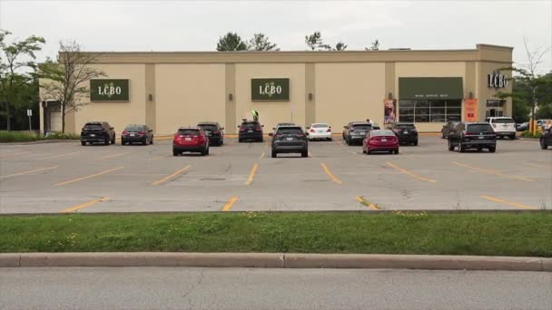 建物および正面玄関のオントリオのロゴの側面のLcboの液体の制御板 前景で渡る車および車が付いている駐車場 広いショット — ストック動画