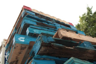 Mavi paletler üst üste kayar, ahşap renkli paletler de arka planda bulanık ağaçlar, alçak açıdan yukarı bakar.