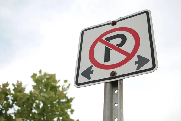 禁止停车标志白色正方形标志 铁柱上有黑字和红字 车架右 天空和树木为背景 — 图库照片