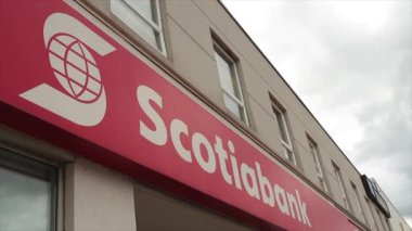 Scotiabank başlığı mağazanın ön girişinde metin logosu yazarken, yukarıda pencereler ve gökyüzü, kırmızı arkaplanda beyaz yazılar