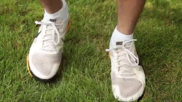 成年男子在草地上来回走动时穿的黄黑相间的白皮鞋 — 图库视频影像