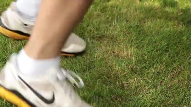 成年男子穿的黄黑相间的白皮鞋 在草地上与屏幕相对的地方边跳边跳 — 图库视频影像