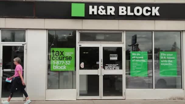 HとRロゴ付きの小さな店のフロントエントランス 歩行者市民の両方の方法で歩く人々 窓のドアの歩道 緑の白と黒 — ストック動画
