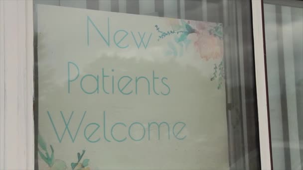 新病人欢迎在窗口内书写字幕文字标志 并在窗口反射时看到通信量 在白色背景上看到绿色文字 — 图库视频影像