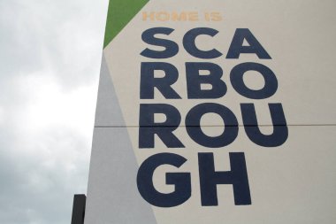 Scarborough metin başlığı binanın yan tarafında dört satırlık siyah büyük harflerle yazılmış beyaz arka plan sağ ekranda gökyüzü sol ekranı ile birlikte.