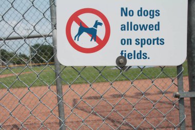 Spor sahalarına köpek giremez. Arka planda beyzbol elması olan tabela, kırmızı ve siyah çizili köpek resmi, beyaz arka planda siyah başlık yazısı, orta resim.