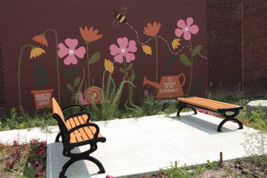 Arkalarında tuğla duvarda pembe çiçek duvar resmi olan betonda karşı karşıya duran iki sırık.