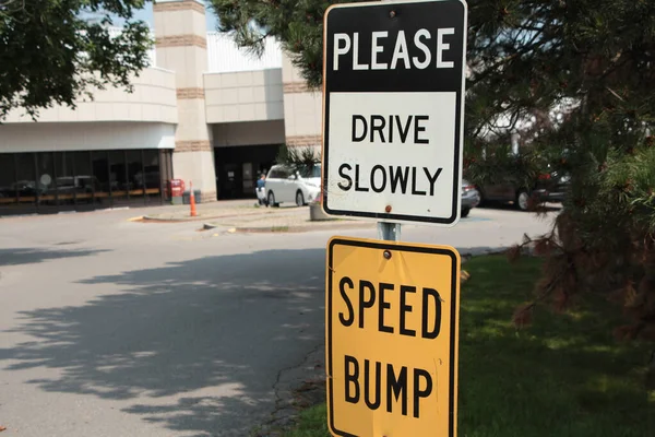 请慢慢驾驶金属矩形标志和车速颠簸标志一个接一个 黑色和白色标题文字黄色 仍然平静的背景停车场 — 图库照片