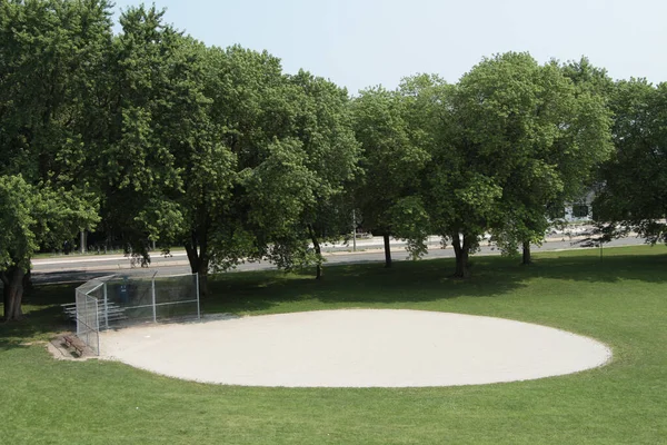 灰蒙蒙的砾石圆圆的棒球场 身后有路 有树木 家里底板上有银白色的菱形篱笆 周围是草 从高处朝下看去 — 图库照片
