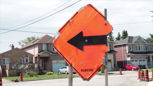 在住宅区街道上 用黑色箭头指向左边 汽车向同一方向驶去 砸碎受损的橙色菱形建筑标志 — 图库视频影像