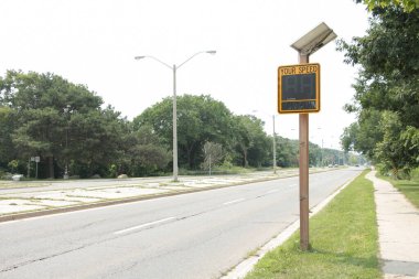 Güneş enerjili elektronik sarı ve siyah. Hız levhan yolun yanındaki tahta direkte. Üzerinde güneş paneli var.