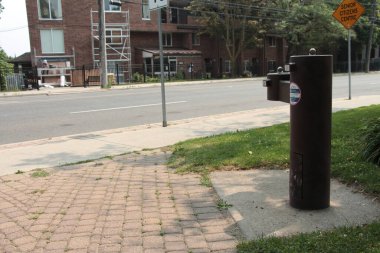 Kahverengi halka açık çifte su içme çeşmesi. Park parkette çimento plakasının üzerinde ikinci bir kaldıraç var.