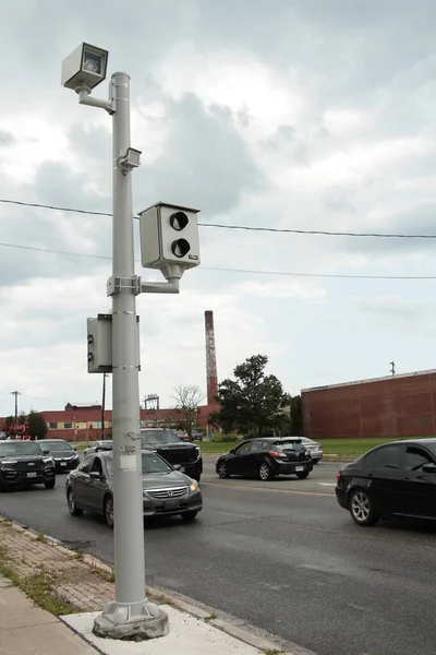 赤いライト カメラの映像およびビデオ銀製のポストの2つのカメラ それの隣に道を渡るすべての暗い車の交通および背後で暗い曇った空 肖像画 — ストック写真